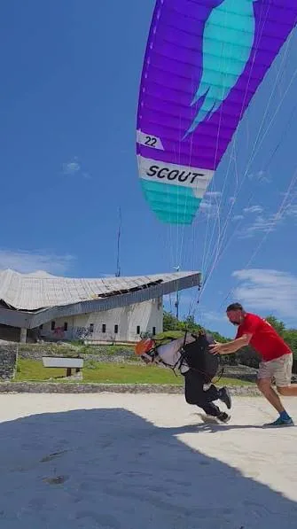 Student running with a parakite overhead while the instructor runs alongside